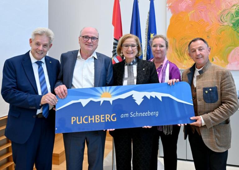 fünf Personen stehen nebeneinander und halten ein Schild in die Kamera