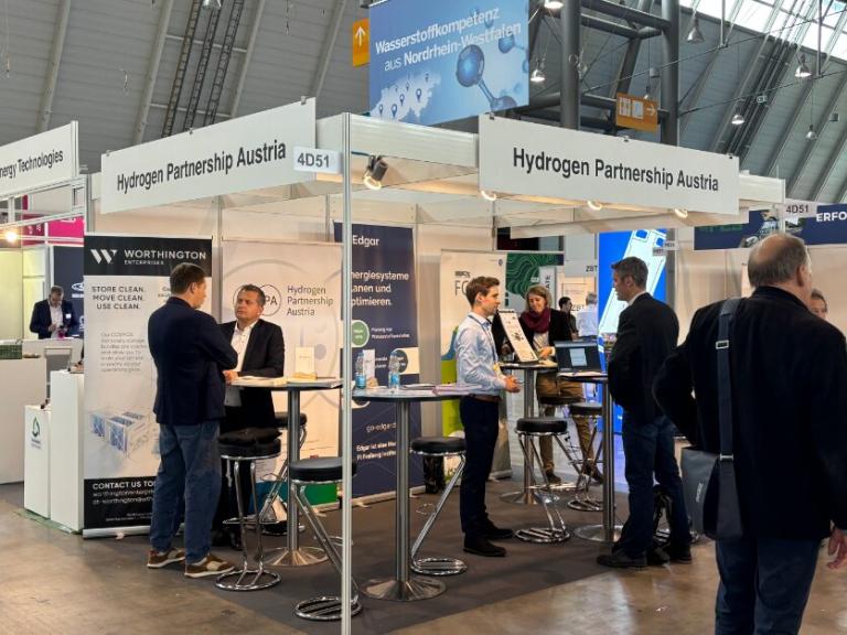 Personen stehen um einen Messestand herum