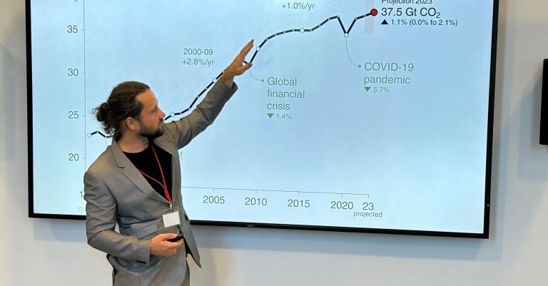 Mann hält einen Vortrag und zeigt mit Finger auf die PowerPoint Präsentation