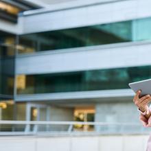 Internationale junge Businesslady mit tablet vor einem modernen Bürogebäude