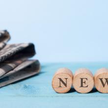 Stapel Zeitungen links und rechts kleine Holzsteine mit News-Schriftzug