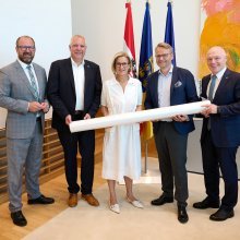Fünf Personen stehen in einem Büro- bzw. Besprechungsraum vor den Flaggen von Österreich, Niederösterreich und der Europäischen Union.