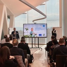 Vortragsraum mit vortragenden Personen und Publikum