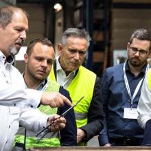 Person zeigt anderen Personen einen Gegenstand