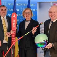 drei Personen stehen in einer Reihe und halten einen Ski