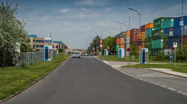 Parkbucht, Beschilderung und Straße mit Containerlager im IZ NÖ-Süd