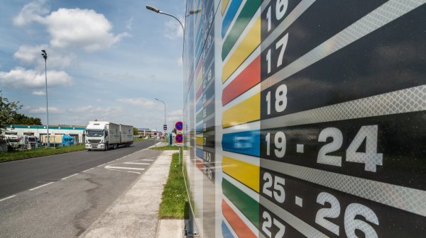 Bunte Tafel mit Wegeleitsystem und Straße mit LKW