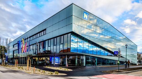 Außenansicht modernes Gebäude mit Glasfassade und Fahnen davor