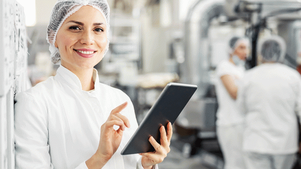 Dame mit Ipad steht in einem lebensmittelverarbeitenden Betrieb
