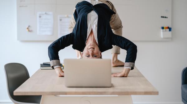 Businesslady im Anzug macht Yoga-Brücke am Tisch