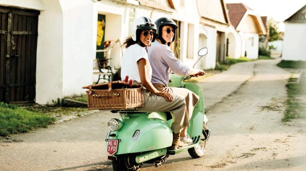 Zwei junge Frauen auf Moped in einer Kellergasse