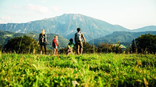vier Personen stehen auf einer Wiese und im Hintergrund befindet sich ein Berg