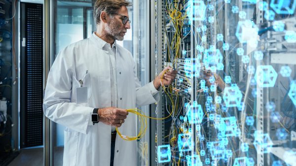 Älterer männlicher Techniker beim Einstecken von Glasfaserkabeln im Rechenzentrum