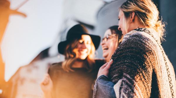 drei Frauen stehen nebeneinander und lachen
