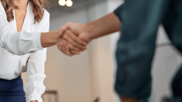 Junge Dame in Businesskleidung schüttelt Geschäftspartner die Hand