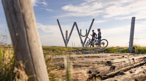 Zwei Mountainbiker auf den Wexl-Trails mit Bilderungstafeln und Aussicht