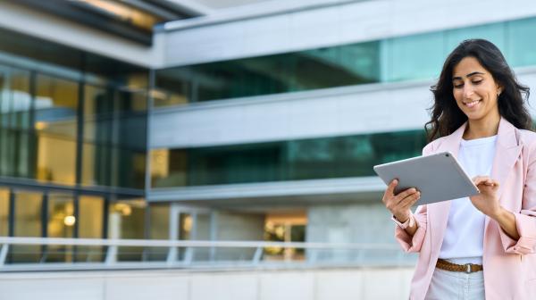 Internationale junge Businesslady mit tablet vor einem modernen Bürogebäude