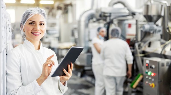 Dame seht mit Tablett in einem lebensmittelverarbeitenden Labor