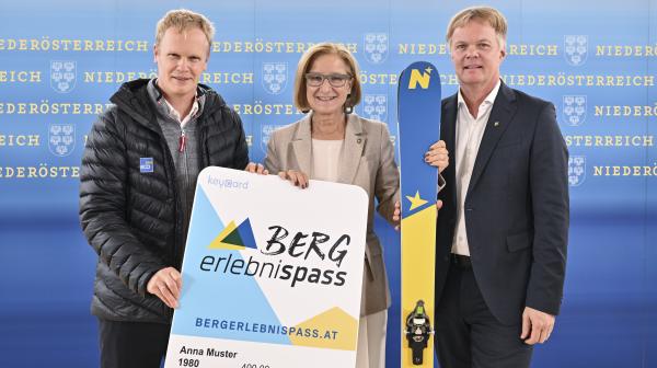 3 Personen stehen mit blau-gelben Ski und großem Bergerlebnis-Pass