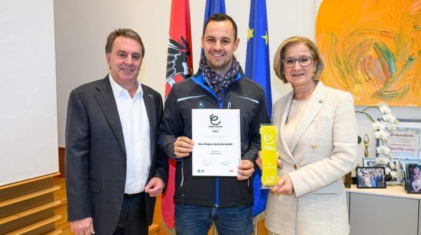 drei Personen stehen nebeneinander und lachen in die Kamera