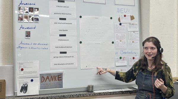 Dame steht vor Tafel und erklärt etwas