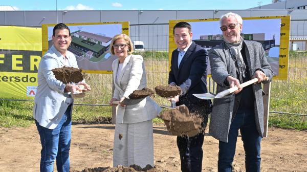 vier Personen stehen mit einem Spaten nebeneinander und schaufeln Erde