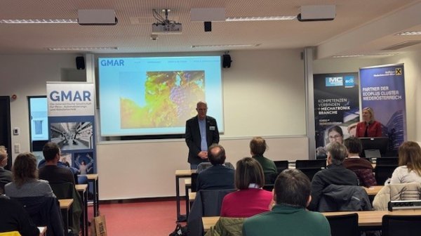 Mann hält Präsentation mit PowerPoint vor kleiner Gruppe