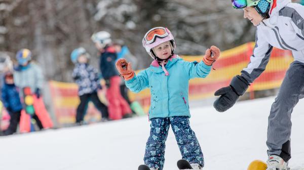 Kind auf Ski mit Mutter in einem Kinderskiland