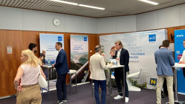 Messestand mit mehreren Personen, die an Stehtischen gerade beraten werden.