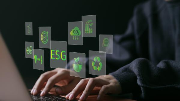 schreibende Finger auf Laptop zu sehen mit Icons rund um das Thema ESG