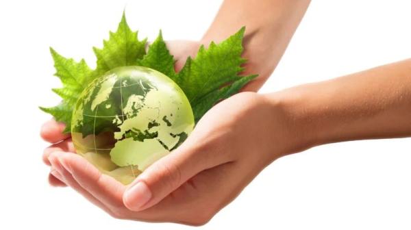 Hand hält grüne Glas-Erdkugel in Händen