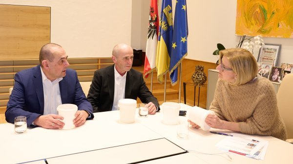 drei Personen sitzen auf einem Tisch und reden