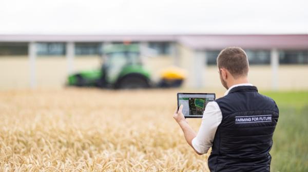 Mann steht mit IPad am Feld