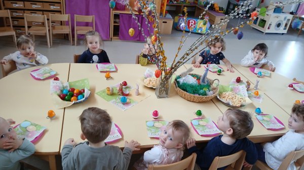 Kindergartenkinder sitzen an österlich gedeckten Tischen
