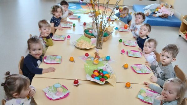 Kindergartenkinder sitzen an österlich gedeckten Tischen