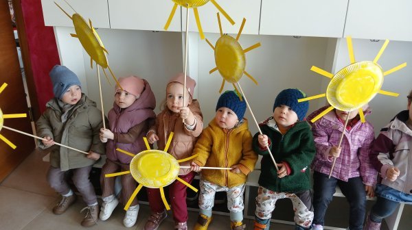 Kindergartenkinder warten mit selbstgebastelten Sonnen in der Garderobe