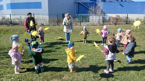 Kindergartenkinder stehen mit ihren selbstgebastelten Sonnen im Garten