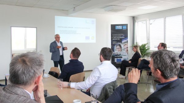 Vortragssituation mit einem Vortragenden und einigen Zuhörern