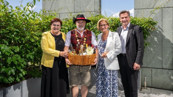 Gruppenfoto bei einer Veranstaltung: vier Personen, darunter ein Mann in Tracht mit Auszeichnung