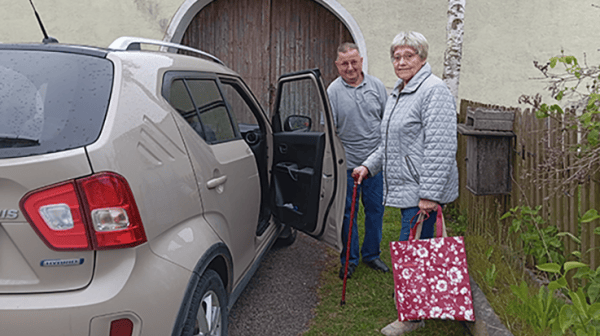 zwei Personen stehen neben einem Auto