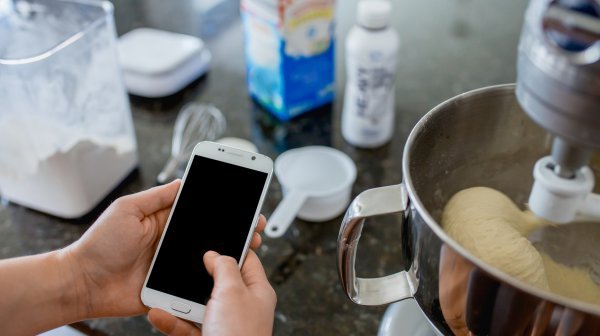 Backsituation und Person sucht Rezept am Handy