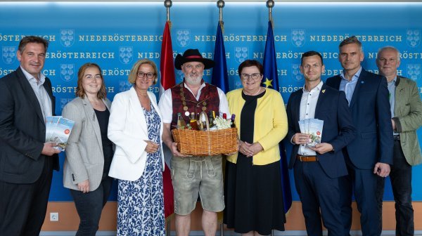 Gruppenfoto mit sieben Personen bei einer Veranstaltung, darunter ein Mann in Tracht
