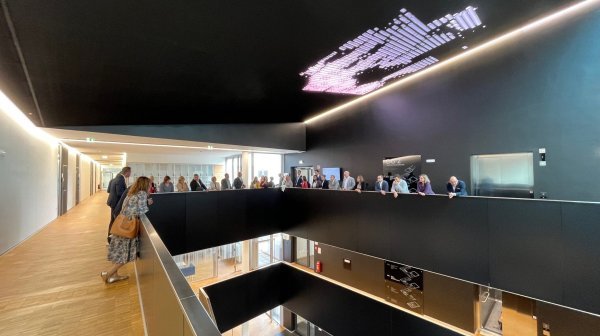 Gang oder Raum mit schwarzer Decke und Holzboden mit ein paar Personen