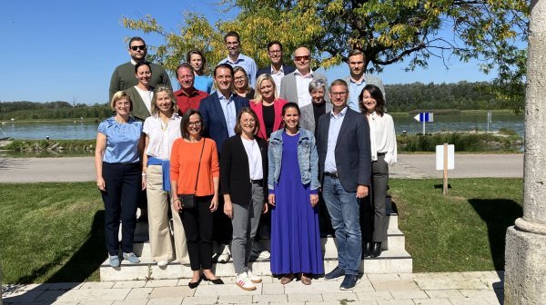 Gruppenfoto mit 19 Personen auf einer Stiege im Freien neben einem Baum