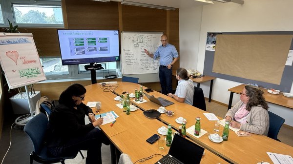 Workshop-Setting mit einer Kleingruppe und Vortragendem 