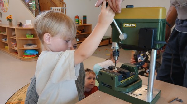 Kindergartenkinder mit Betreuerin bohren Löcher in Kastanien