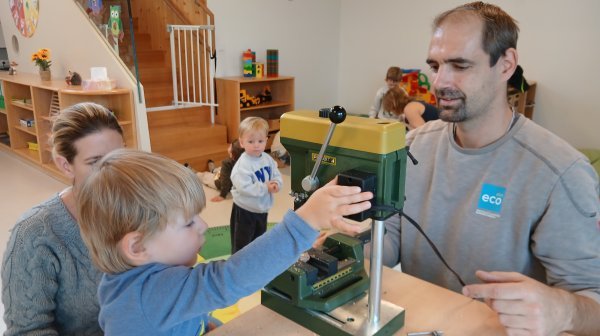 Kindergartenkinder mit Betreuer bohren Löcher in Kastanien