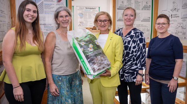 Gruppenfoto nur mit Frauen wo ein großer Sack mit Perlit-Füllung in die Kamera gehalten wird