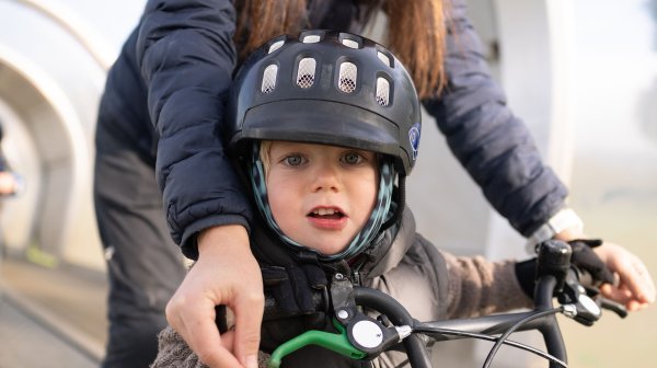 Mutter mit kleinem Sohn auf Fahrrad auf einem Förderband