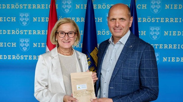LH Mikl-Leitner mit Herrn Kasseckert von DPM vor einer Niederösterreich-Wand mit Fahnen